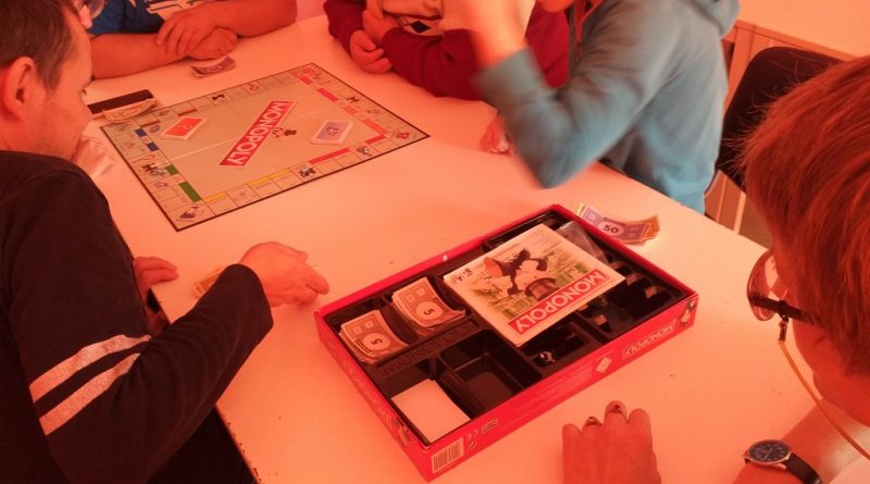 Uczestnicy Domu grają w grę planszową przy stole
