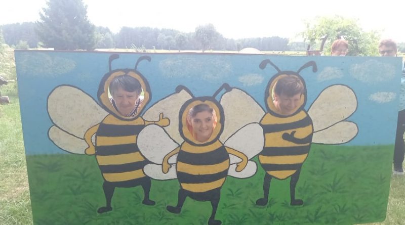 Uczestnicy Środowiskowego Domu Samopomocy w Czarnowie pozują do zdjęcia na tle malowanych pszczółek.