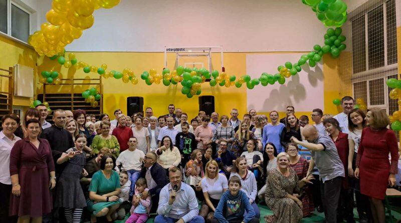 Wspólne zdjęcie uczestników Domu wraz z gośćmi na balu andrzejkowym w udekorowanej balonami sali gimnastycznej.